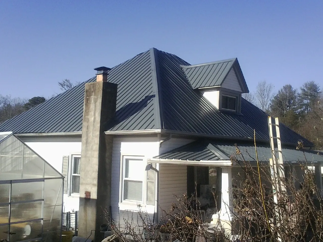 Dark blue standing seam metal roof on a white farmhouse with dormer — Slate & Tile Roof Repair by Roofing Brothers in Grayslake