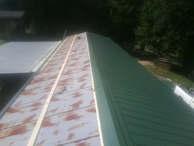Old rusted panels beside newly installed green metal roofing — Wind Damage Roof Repair by Roofing Brothers in Grayslake