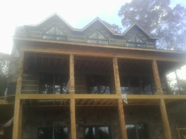 Dormers and porch framing on a large log home under construction — Roof Coating work by our crew in Grayslake
