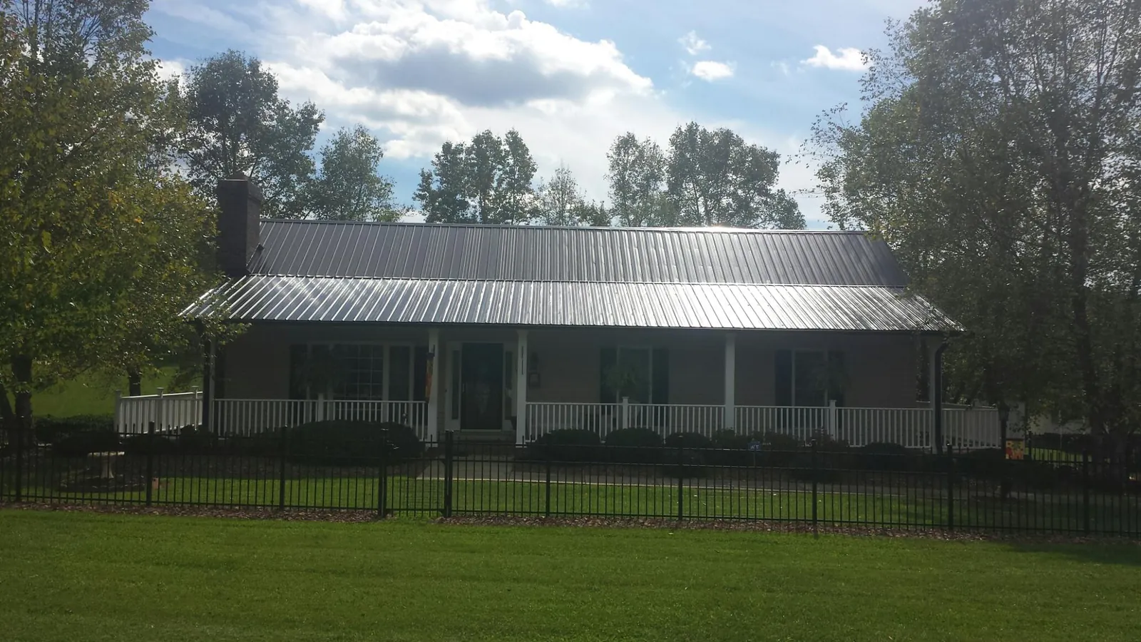 Gray metal roof on a brick ranch with a full width front porch — Gutter Guard Installation work by our crew in Grayslake