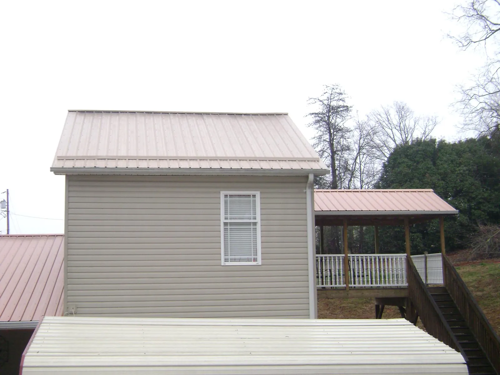 Tan metal roofs on a two story addition and attached porch, from a Roof Replacement job in Grayslake