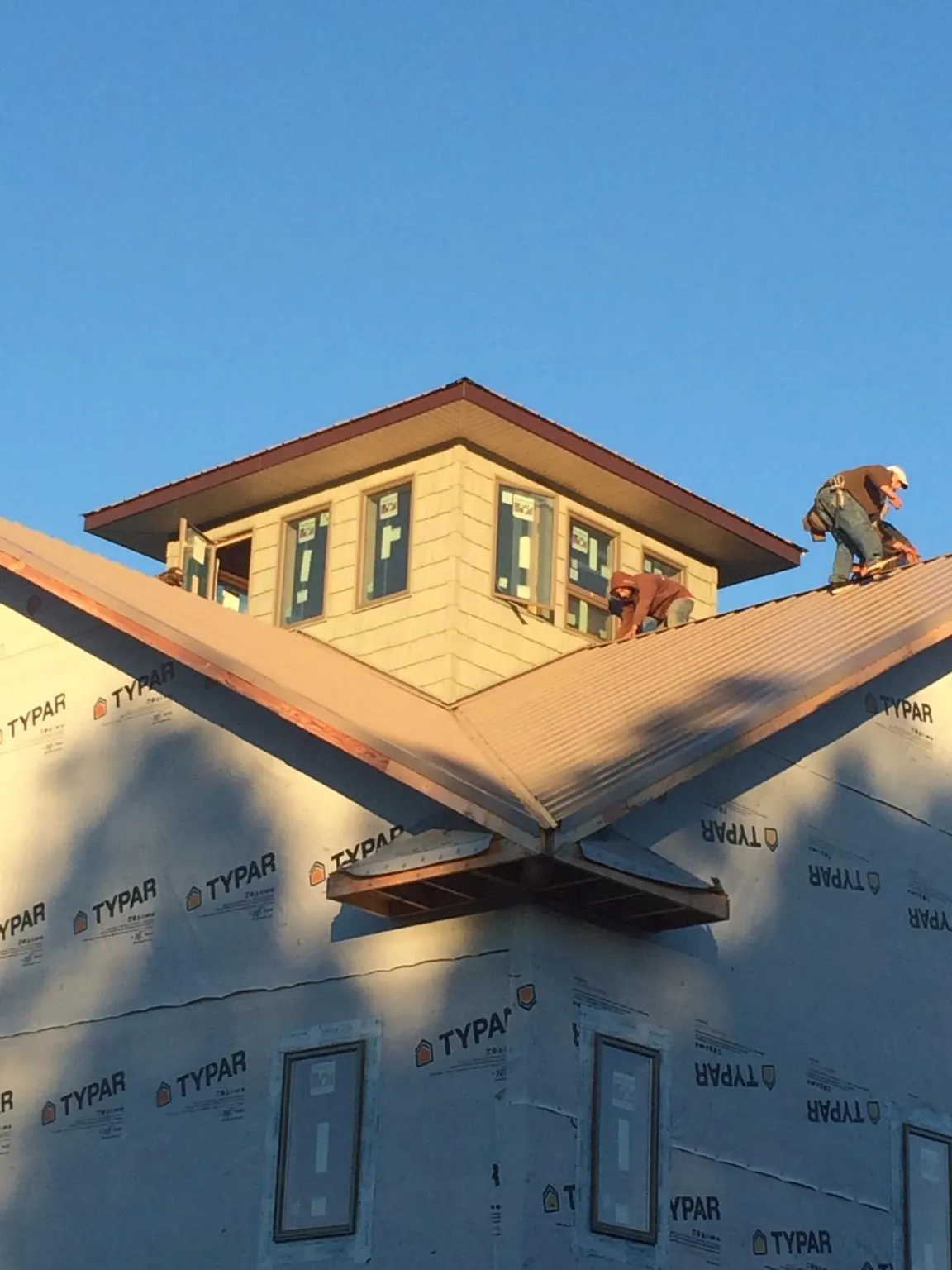 Roofers working around a rooftop cupola on a new metal roof at sunset — Roof Waterproofing in Grayslake by Roofing Brothers